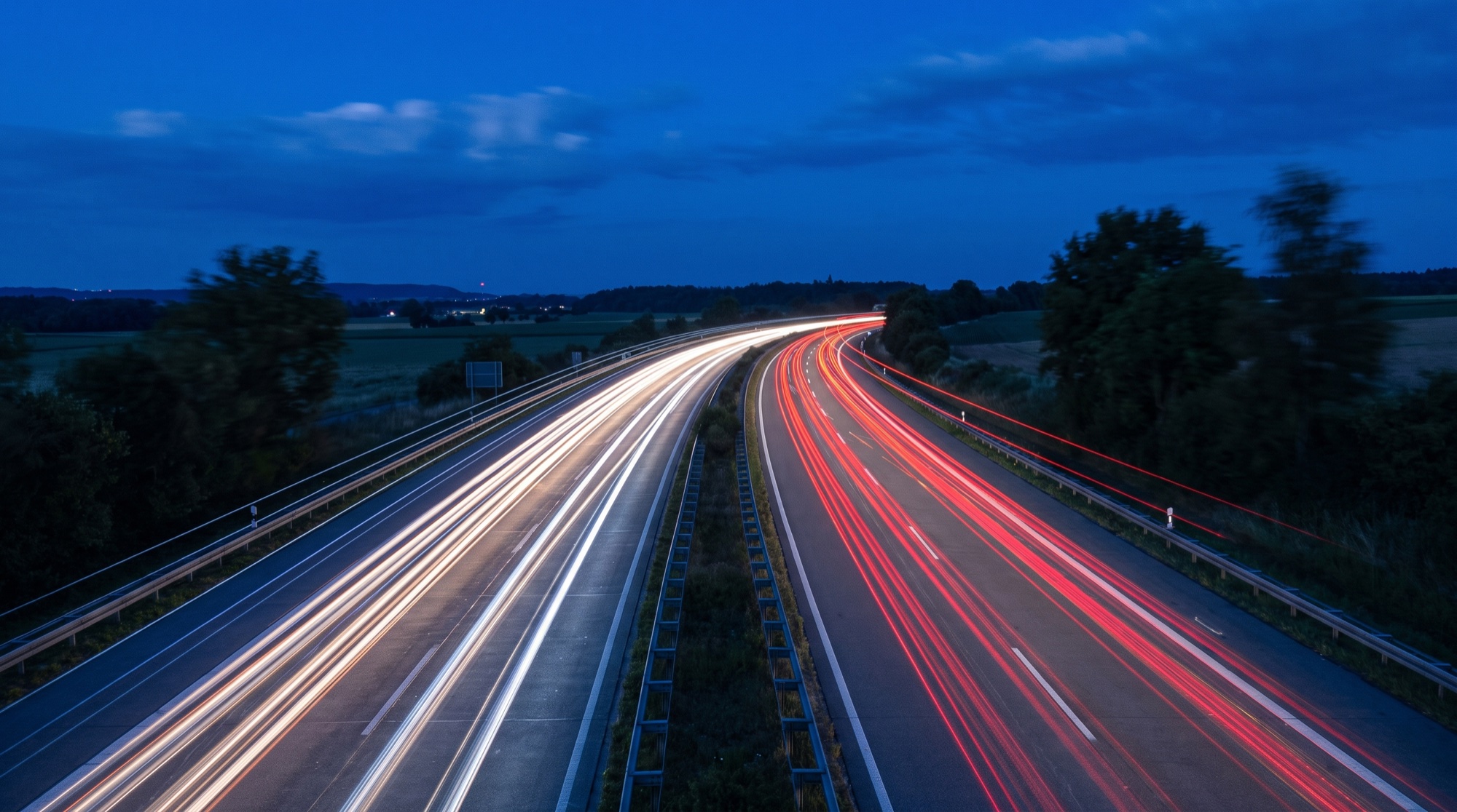 Autobahn zur blauen Stunde mit Lichtspuren vorbeifahrender Fahrzeuge