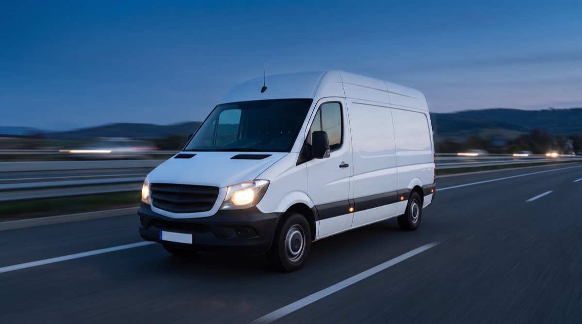 Weißer Transporter unterwegs auf der Autobahn in der Dämmerung